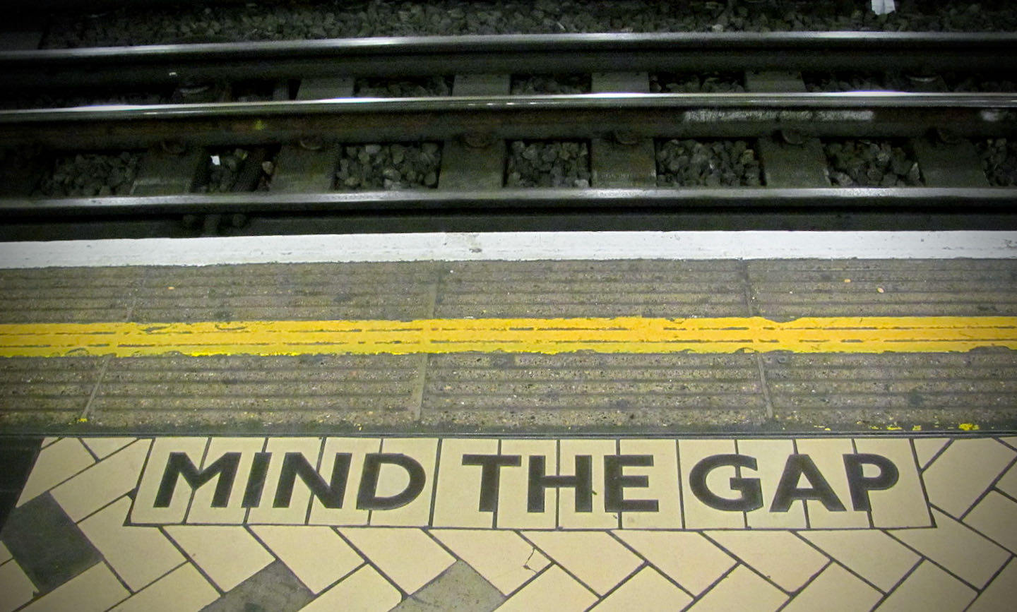 A picture of a subway station with "mind the gap" written on the floor.
